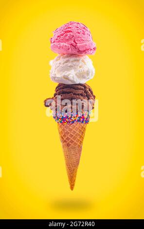 Eiskegel mit Erdbeer-Vanille und Schokolade in einem spitzen Zuckerkegel, der in der Luft schwimmt Stockfoto