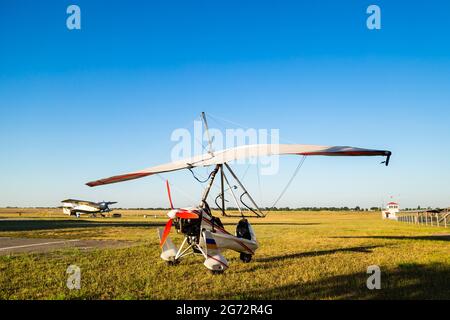 Motor Hängegleiter steht auf grünem Gras auf dem Flugplatz, heller Sommertag Stockfoto