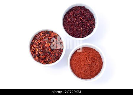 Set aus drei Schüsseln mit roten Gewürzen isoliert auf weißem Hintergrund. Chili, Pfefferpulver, getrocknete Tomaten Draufsicht Stockfoto
