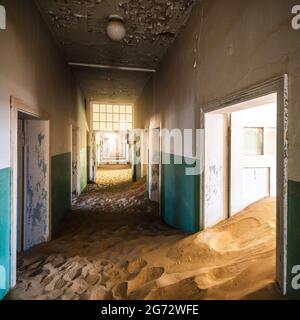 Verlassene Gebäude, die in der alten Bergbaustadt Kolmanskop in der Nähe von Luderitz, Namib-Wüste, Namibia, von eindringenden Sand übernommen wurden. Stockfoto