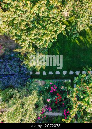 Landschaftsgestaltung mit Blumenbeeten und Pfad, natürliche Landschaftsgestaltung Panorama im Hausgarten. Schöne Aussicht auf schön angelegten Garten in wohngebiet backy Stockfoto