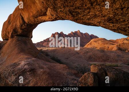 Felsbogen und Granitberge bei Sonnenuntergang in Spitzkoppe, Damaraland, Namib Desert, Namibia. Stockfoto