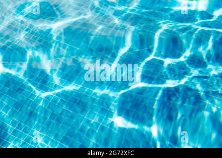 Boden eines Swimmingpools, der Sonnenstrahlen auf blauen quadratischen Fliesen reflektiert. Stockfoto