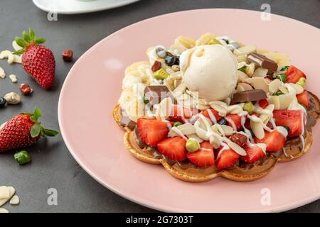 Herzwaffel mit Banane und Erdbeere mit Gummy Candy und Eis darauf. Stockfoto