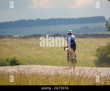 Ein Sportfahrradfahrer auf einer Steinbahn, die die salisbury-Ebene, Wiltshire, Großbritannien, überquert Stockfoto