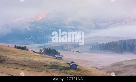 Mystische neblige Sonnenaufgangslandschaft der berühmten Almwiese in den Dolomiten Alpen auf bewölktem Hintergrund Stockfoto