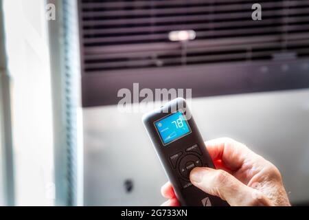 Mann, der eine Fernbedienung zur Steuerung der Fensterklimaanlage verwendet, NYC, USA Stockfoto