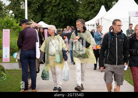 East Molesey, Surrey, Großbritannien. Juli 2021. Es war ein sehr geschäftiger Tag heute am 4. Tag des RHS Hampton Court Palace Garden Festivals. Im echten britischen Stil schien die Sonne am Morgen, aber am Nachmittag folgten heftige Duschen, da Sonnenschirme und Ponchos die Accessoires waren, die man unbedingt haben sollte. Quelle: Maureen McLean/Alamy Stockfoto