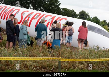 East Molesey, Surrey, Großbritannien. Juli 2021. Die Menschen stehen Schlange, um den sehr beliebten Global Impact Garden, Extinction von Designr Felecity O'Rourke, zu sehen. Es war ein sehr geschäftiger Tag heute am 4. Tag des RHS Hampton Court Palace Garden Festivals. Im echten britischen Stil schien die Sonne am Morgen, aber am Nachmittag folgten heftige Duschen, da Sonnenschirme und Ponchos die Accessoires waren, die man unbedingt haben sollte. Quelle: Maureen McLean/Alamy Stockfoto