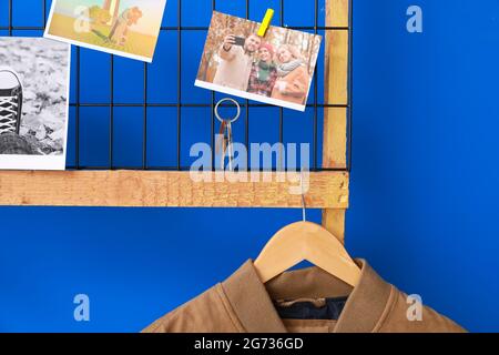 Halter mit Schlüssel, Bilder und Kleidung hängen an der farbigen Wand Stockfoto