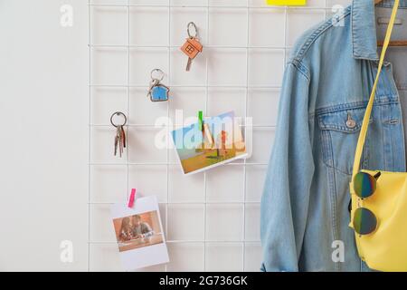 Halter mit Schlüsseln, Kleidung und Bildern, die an der hellen Wand hängen Stockfoto