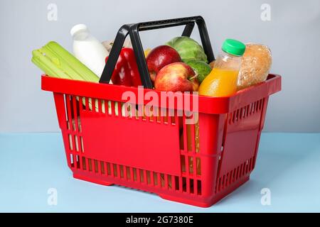 Warenkorb mit Lebensmitteln auf farbigem Hintergrund Stockfoto