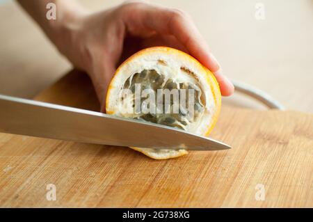 Frische, reife Bio-Granadilla oder gelbe Passionsfrucht, halbiert auf einem Holzbrett. Exotische Früchte, gesunde Ernährung Konzept Stockfoto