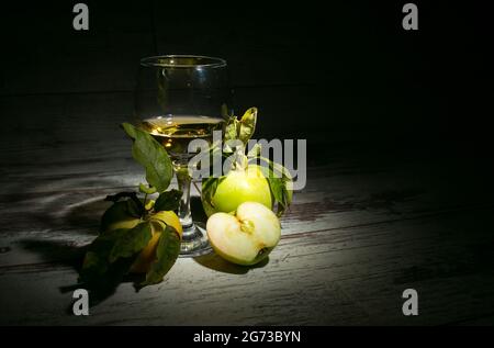 Der Herbst ist die Jahreszeit der Weinherstellung. Komposition mit einem Glas Apfelmost und frischen gelben Äpfeln auf einem hölzernen Hintergrund. Stockfoto