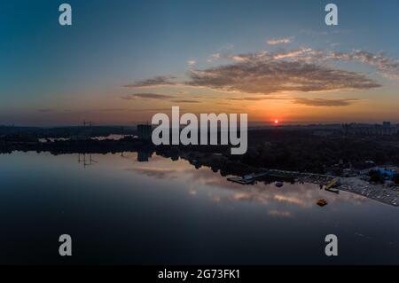 Landschaftlich reizvolle Sonnenaufgangssicht mit Wolken, die sich in einer spiegelnden Wasseroberfläche auf einem breiten Fluss spiegeln. Am frühen Morgen, Morgendämmerung in Charkiw Zhurawliwskyy Hidropark fr Stockfoto