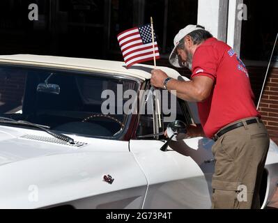 Ein Mann installiert eine kleine amerikanische Flagge auf seinem alten Chevrolet Corvette Cabriolet, das auf einer Oldtimer-Show am 4. Juli in Santa Fe, NM, ausgestellt wird. Stockfoto