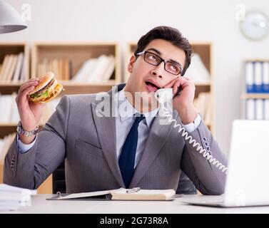 Die hungrigen lustig Geschäftsmann Essen der Trödelnahrung Sandwich Stockfoto