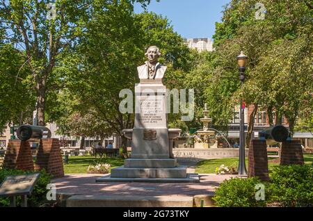 Johnstown, PA, USA - 11. Juni 2008: Joseph Johns Statue im Central Park mit 2 Kanonen vorne und Brunnen hinten. Grünes Laub unter blauem Himmel wit Stockfoto