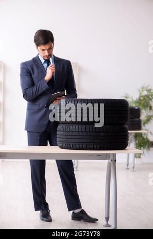 Junger Geschäftsmann, der Reifen im Büro inspiziert Stockfoto