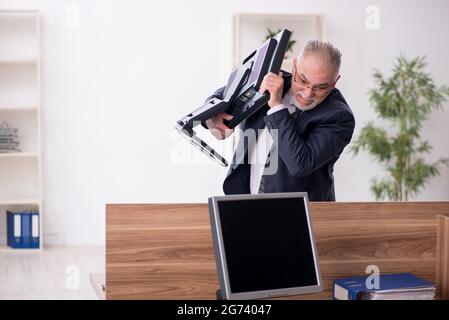 Gealterter Geschäftsmann, der am Arbeitsplatz sitzt Stockfoto