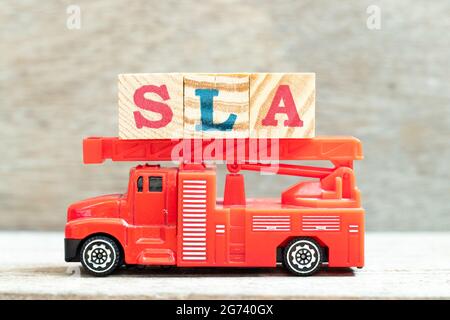 Feuerwehrwagen mit Buchstabenblock in Wort SLA (Abkürzung für Service Level Agreement) auf Holzhintergrund Stockfoto