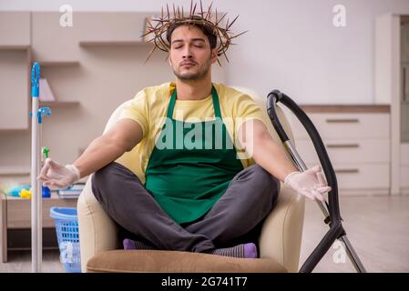 Junger männlicher Auftragnehmer, der auf dem Kopf einen stacheligen Kranz trägt und Hausarbeit leistet Stockfoto