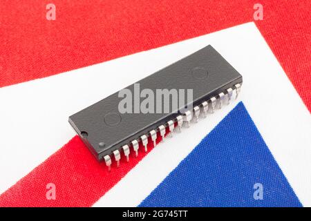 Nahaufnahme des integrierten Schaltkreises/EPROM-Chips auf der kleinen UK Union Jack-Flagge. Bei Halbleitermangel in Großbritannien, Abhängigkeit von britischen Chips, Start-ups von britischen Chips. Stockfoto