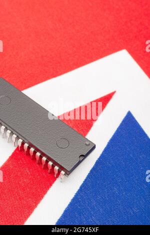 Nahaufnahme des integrierten Schaltkreises/EPROM-Chips auf der kleinen UK Union Jack-Flagge. Bei Halbleitermangel in Großbritannien, Abhängigkeit von britischen Chips, Start-ups von britischen Chips. Stockfoto