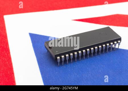 Nahaufnahme des integrierten Schaltkreises/EPROM-Chips auf der kleinen UK Union Jack-Flagge. Bei Halbleitermangel in Großbritannien, Abhängigkeit von britischen Chips, Start-ups von britischen Chips. Stockfoto