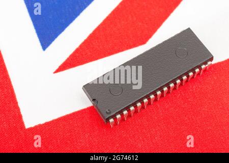 Nahaufnahme des integrierten Schaltkreises/EPROM-Chips auf der kleinen UK Union Jack-Flagge. Bei Halbleitermangel in Großbritannien, Abhängigkeit von britischen Chips, Start-ups von britischen Chips. Stockfoto