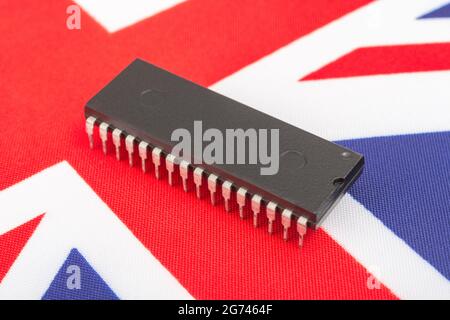 Nahaufnahme des integrierten Schaltkreises/EPROM-Chips auf der kleinen UK Union Jack-Flagge. Bei Halbleitermangel in Großbritannien, Abhängigkeit von britischen Chips, Start-ups von britischen Chips. Stockfoto