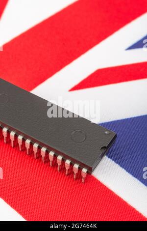 Nahaufnahme des integrierten Schaltkreises/EPROM-Chips auf der kleinen UK Union Jack-Flagge. Bei Halbleitermangel in Großbritannien, Abhängigkeit von britischen Chips, Start-ups von britischen Chips. Stockfoto