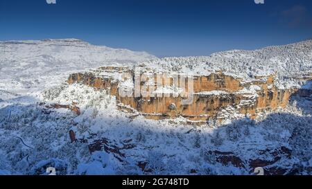 Schneebedeckte Siuranella-Klippen im Winter, vom Dorf Siurana aus gesehen. Im Hintergrund der Berg Montsant (Priorat, Tarragona, Katalonien, Spanien) Stockfoto