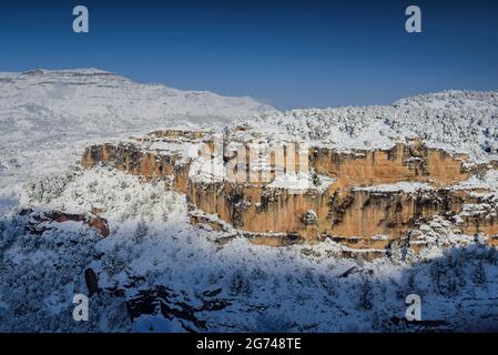 Schneebedeckte Siuranella-Klippen im Winter, vom Dorf Siurana aus gesehen. Im Hintergrund der Berg Montsant (Priorat, Tarragona, Katalonien, Spanien) Stockfoto