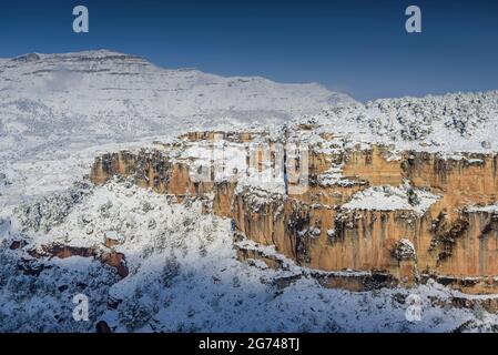 Schneebedeckte Siuranella-Klippen im Winter, vom Dorf Siurana aus gesehen. Im Hintergrund der Berg Montsant (Priorat, Tarragona, Katalonien, Spanien) Stockfoto