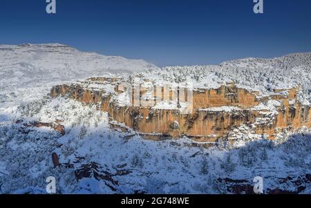 Schneebedeckte Siuranella-Klippen im Winter, vom Dorf Siurana aus gesehen. Im Hintergrund der Berg Montsant (Priorat, Tarragona, Katalonien, Spanien) Stockfoto