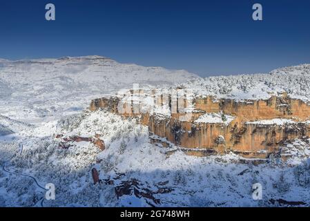 Schneebedeckte Siuranella-Klippen im Winter, vom Dorf Siurana aus gesehen. Im Hintergrund der Berg Montsant (Priorat, Tarragona, Katalonien, Spanien) Stockfoto