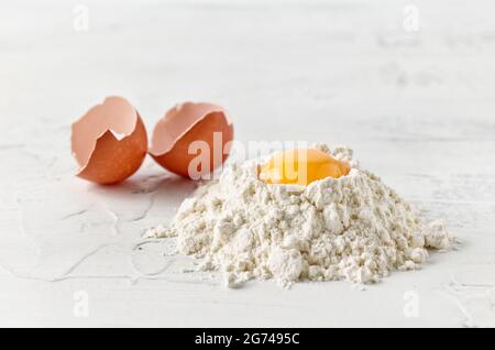 Mehl und Eigelb auf weißem Küchentisch Stockfoto