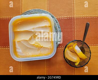 Eine Wanne mit köstlichem Mango-Sorbet auf einem orangefarbenen und roten Tischtuch Stockfoto