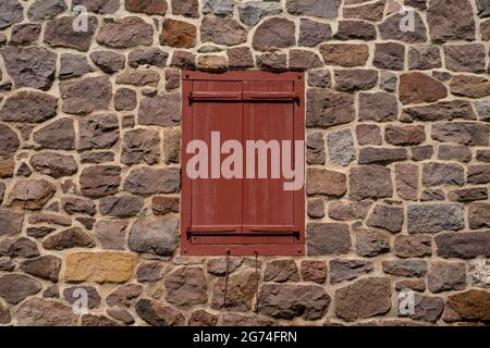 Geschlossene, antike rote Fensterläden mit Steinwänden Stockfoto