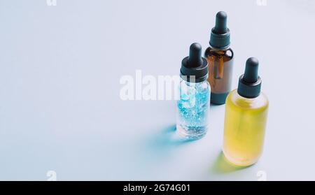 Kosmetische Produkte Gel-Serum-Gleitmittel Hyaluronsäure mit Sauerstoffblasen Glasfläschchen mit einem Pipette blauen Hintergrund Stockfoto