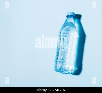 Reines Trinkwasser in einer transparenten Plastikflasche auf blauem Hintergrund. Stockfoto