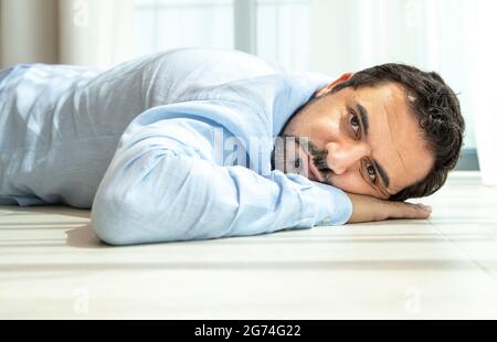 Gelangweilter arabischer Mann mittleren Alters, der auf dem Boden ruht Stockfoto