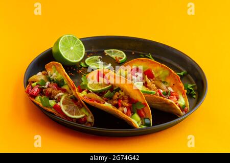 Mexikanischer Taco in schwarzer Pastete auf gelbem Hintergrund Stockfoto