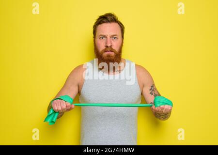 Mann mit Bart und Tattoos trainiert mit einem Gummiband Stockfoto