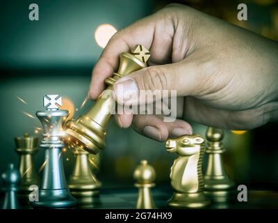 Hand Geschäftsmann bewegen den goldenen König Schach kämpfen silbernen König mit Feuer Funken Schach auf dem Schachbrett, um erfolgreich im Wettbewerb. Manager Stockfoto