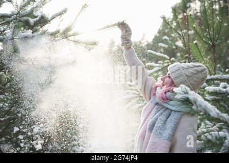 Schönes Mädchen mit rosa Haaren weht Schnee von Bäumen Stockfoto