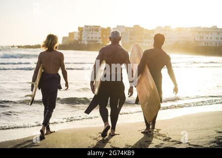 Surferfreunde mit mehreren Generationen haben Spaß beim Surfen am Strand - Schwerpunkt auf Senioren Stockfoto