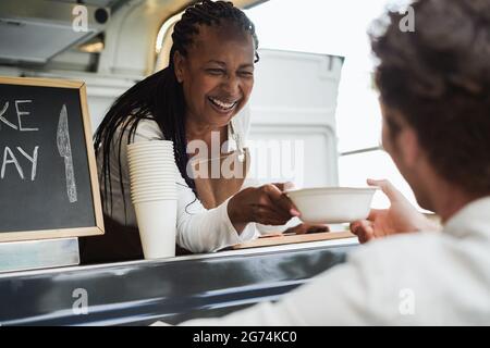 African american Senior Woman Serving take away Food inside Food Truck - Focus on female face Stockfoto