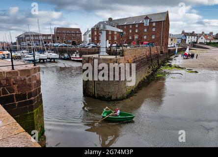 Mann rudert ein kleines Boot aus dem Hafen von North Berwick in West Bay East Lothian, Schottland, Großbritannien Stockfoto